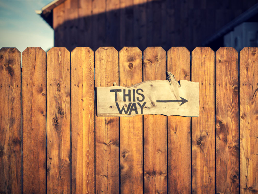 Sign on barn fence says This Way